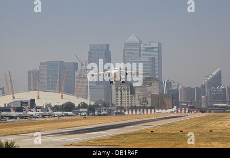 Un British Aerospace 146 decolla dall'Aeroporto di London City con Canary Wharf e il Millennium Dome in background Foto Stock