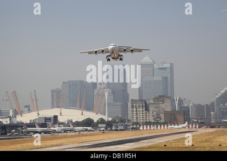 Un British Aerospace jet 146 prende il volo all'Aeroporto di London City con Canary Wharf e il Millennium Dome in background Foto Stock