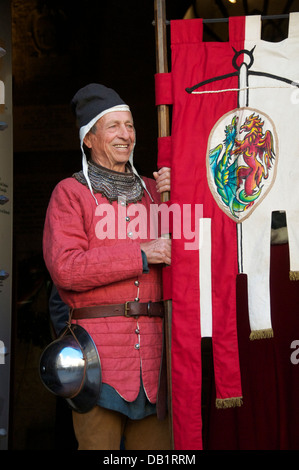 Uomo vestito in costume medievale tenendo un banner Volterra Toscana Italia Foto Stock