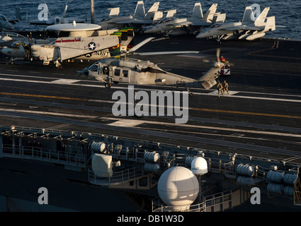 Velisti assegnati per l'eliminazione degli ordigni esplosivi unità mobile (EODMU) 5 condurre un rapido esercizio di corda da un MH-60S Seahawk con il "Golden falchi' di elicottero di mare squadrone di combattimento (HSC) 12 sul ponte di volo dell'U.S. La marina è distribuita aircraf Foto Stock