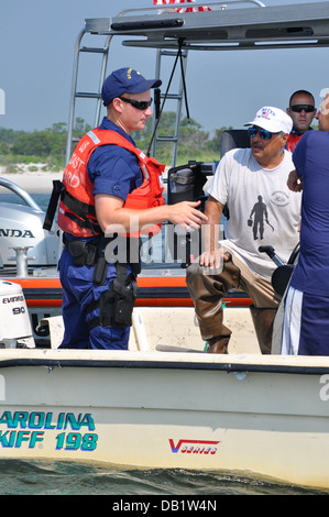 Petty Officer 2a classe John Lowell, un funzionario d'imbarco dalla stazione della Guardia Costiera di Jones Beach, conduce un controllo di sicurezza a bordo di una nave da diporto nei pressi di Jones ingresso, N.Y., luglio 19, 2013. La guardia costiera della squadre di imbarco ispezionare le navi per la documentazione, li Foto Stock