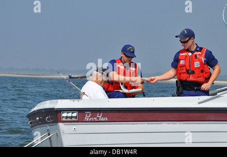 Petty Officer 2a classe John Lowell, un funzionario d'imbarco dalla stazione della Guardia Costiera di Jones Beach, dà un diportista più la registrazione di imbarco al membro del team marinaio Luca Bennett per controllare la conformità durante una nave di ispezione di sicurezza vicino Jones ingresso, N.Y., Luglio Foto Stock