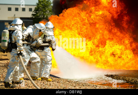 Stati Uniti Air Force vigili del fuoco da sinistra a destra, Senior Airman Joshua Cox, Dustin Lawrence e lo Staff Sgt. Anthony Palestro, estinguere la masterizzazione di propellente a getto 8 carburante durante un'esercitazione a fuoco durante l'esercizio Global Medic, Fort McCoy, Wis., luglio 19, 2013. Foto Stock