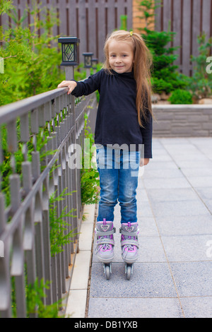 Poco carino girl su pattini a rotelle davanti a casa sua Foto Stock