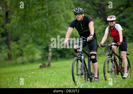 Foto di Felice l uomo e la donna che esercitano con le biciclette all'aperto, in foresta Foto Stock