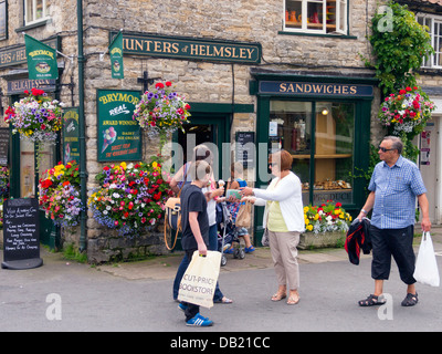 Persone che acquistano il gelato in un giorno caldo presso il cacciatore di Helmsley una qualità fruttivendolo specializzato in locali producono dello Yorkshire Foto Stock