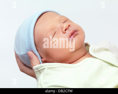 Closeup ritratto di un simpatico neonato ragazzo nella madre le mani isolati su sfondo bianco Foto Stock