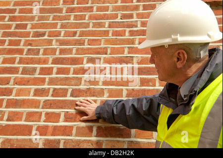 Un edificio ispettore esaminando e a contatto con la parete esterna di un edificio. Foto Stock