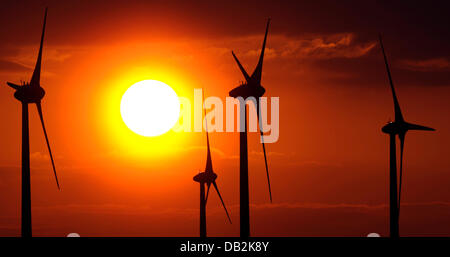 FILE - Un archivio foto datata 17 aprile 2011 mostra il sole che tramonta dietro le ruote del vento vicino Tiefenthal, Germania. Il Cancelliere Merkel intende inoltrare l'energia trun. Contrariamente alle precedenti aspettative del governo i cittadini potrebbero pagare di più per la promozione di eco-energia elettrica nel 2012. Foto: Marius Becker Foto Stock