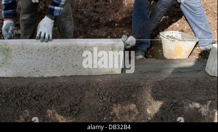 Sito in costruzione - Lavoratori posa del calcestruzzo cordoli Foto Stock