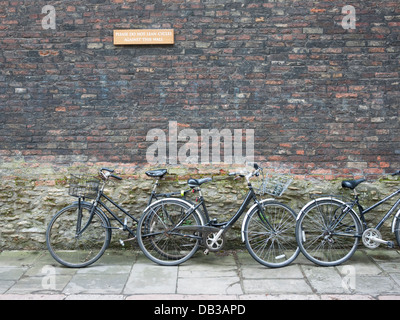 Biciclette appoggiata contro una parete a Cambridge Regno Unito sotto un segno dicendo no cicli Foto Stock