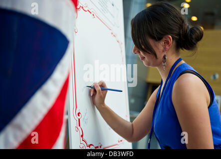 Berlino, Germania. 23 Luglio, 2013. Una donna di segni di una grande carta di congratulazioni per la nascita del Principe di Cambridge presso l' Ambasciata britannica a Berlino, Germania, 23 luglio 2013. Le persone sono stati invitati a firmare la carta presso l'ambasciata. Foto: OLE SPATA/dpa/Alamy Live News Foto Stock