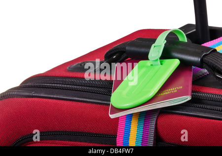 Primo piano di un passaporto e un verde etichetta bagaglio sulla valigia rossa Foto Stock