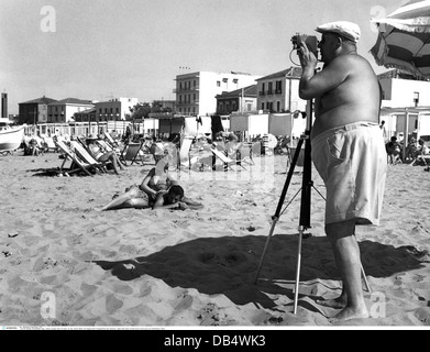 turismo, vita da spiaggia, uomo denso con cappuccio scattando una foto di una coppia che giace nella sabbia, fine degli anni '50, , diritti aggiuntivi-clearences-non disponibile Foto Stock