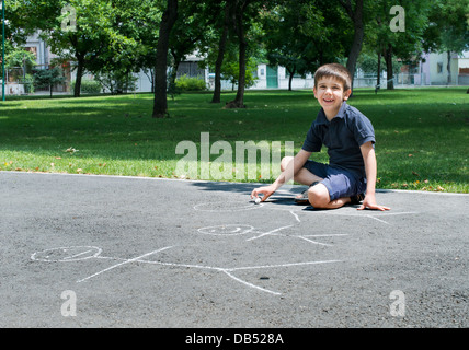 Bambino della famiglia di disegno su asfalto in un parco Foto Stock