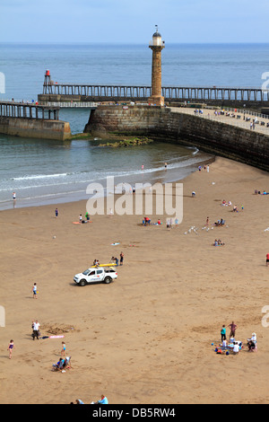 Per i turisti e un bagnino veicolo sulla West Cliff beach dal porto e vecchio faro, Whitby, North Yorkshire, Inghilterra, Regno Unito. Foto Stock