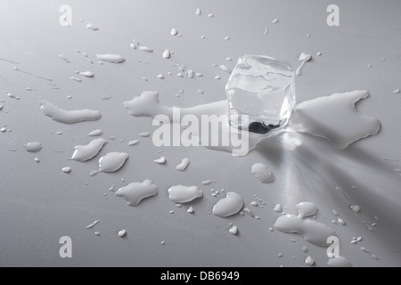 Il cubo di ghiaccio la fusione con pozzanghere di acqua Foto Stock