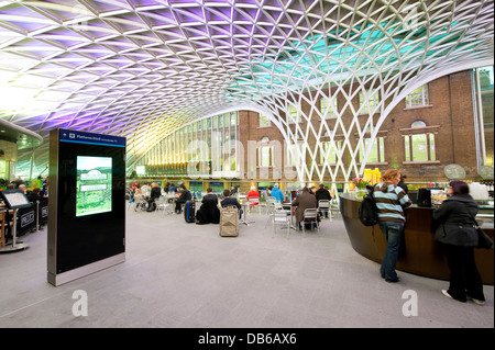 Le persone che hanno preso una pausa nell'atrio occidentale area di Kings Cross stazione ferroviaria di Londra, Inghilterra. Foto Stock