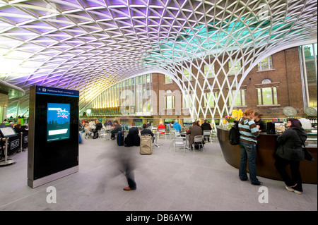 Le persone che hanno preso una pausa nell'atrio occidentale area di Kings Cross stazione ferroviaria di Londra, Inghilterra. Foto Stock