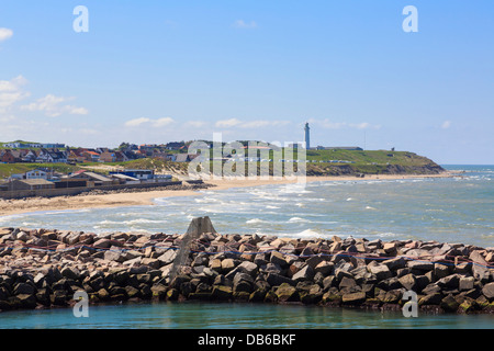 Vista oltre la parete del porto di Tornby Strand spiaggia e faro danese sulla costa nord occidentale. Hirtshals, Nord dello Jutland, Danimarca Foto Stock