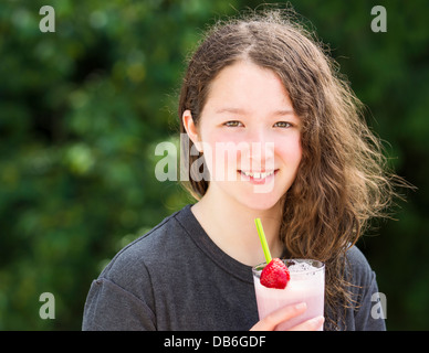 Foto della ragazza giovane azienda frullato fragole all'aperto con uscita sfocata luminose verdi alberi in background Foto Stock