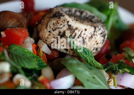 Un piatto di tradizionale formaggio maltese Ġbejna a base di latte di capra o di pecora non pastorizzato coperto di pepe nero e aceto servito con insalata fresca nell'isola di Gozo, l'isola sorella di Malta Foto Stock