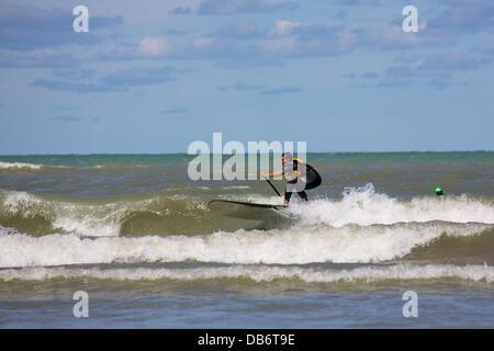 Chicago, Illinois, Stati Uniti d'America. 24 Agosto, 2013. Un uomo su un standup paddle board che naviga in un'onda a Montrose Beach. Un vivace vento del nord soffia per due giorni di portata superiore al normale surf estate al Lago Michigan spiagge e strappato un ondata di calore con lo scambiatore di calore piacevolmente temperature. Credito: Todd Bannor/Alamy Live News Foto Stock