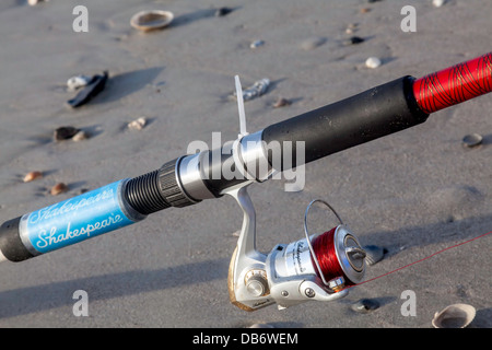 Shakespeare canna da pesca e Mulinello in appoggio sulla spiaggia sabbiosa. Foto Stock