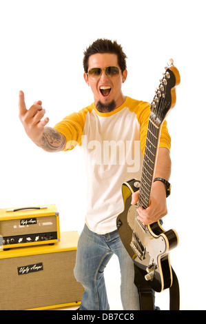 Turbolenti bianco giovane musicista rock holding nero chitarra elettrica puntando il dito giallo amplificatori stack sfondo bianco Foto Stock
