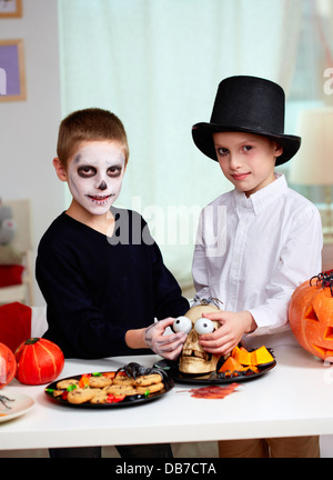 Foto di twin boys holding spooky occhi solo nel cranio eye-socket e guardando la fotocamera Foto Stock