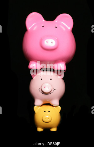 Pressione finanziaria piggy banche su sfondo nero Foto Stock