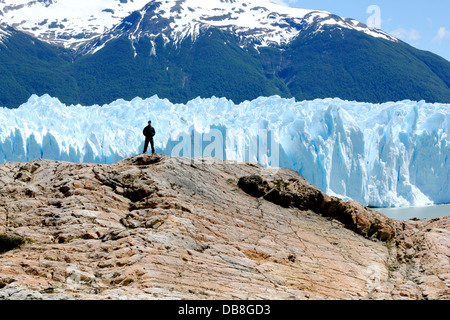 Piccolo uomo in piedi sulla roccia di fronte del ghiacciaio Perito Moreno nel parco nazionale Los Glaciares in Patagonia, Argentina Foto Stock