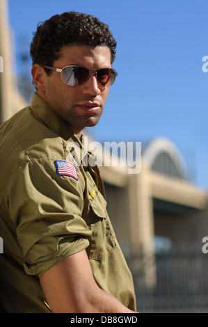 African American l'uomo maschio indossando una maglietta militare e occhiali da sole in posa di fronte a una downtown la bridge Foto Stock