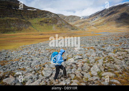 Escursionista femmina escursioni su terreno roccioso in Tjäktjavagge su Kungsleden trail, Lappland, Svezia Foto Stock