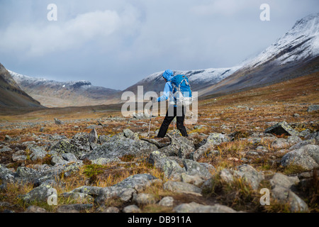 Escursionista femmina escursioni su terreno roccioso in Tjäktjavagge su Kungsleden trail, Lappland, Svezia Foto Stock