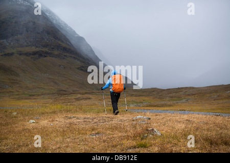 Escursionista femmina orologi come autunno tempesta di neve si avvicina in Tjäktjavagge su Kungsleden trail, Lappland, Svezia Foto Stock