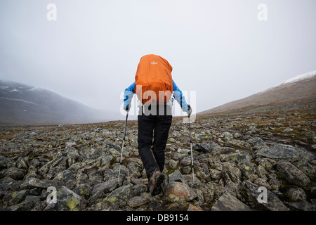 Escursionista femmina escursioni su terreno roccioso in Tjäktjavagge su Kungsleden trail, Lappland, Svezia Foto Stock