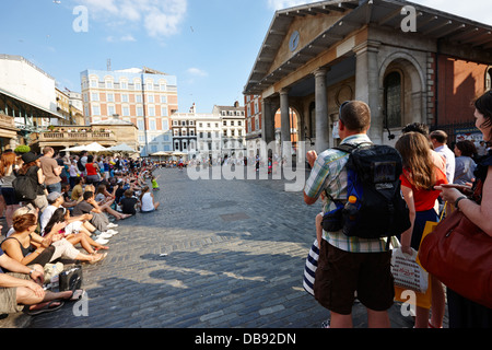 I turisti a guardare gli artisti di strada a Covent Garden Londra Inghilterra REGNO UNITO Foto Stock