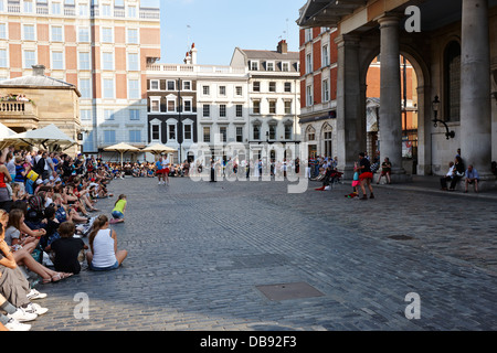 I turisti a guardare gli artisti di strada a Covent Garden Londra Inghilterra REGNO UNITO Foto Stock