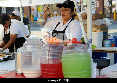 Donna orchata versare in un bicchiere. Due tipi di fruttato liquados (destra) a livello locale street fair in Chicago Foto Stock