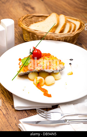 Pesce al forno con patate in salsa di pomodoro Foto Stock