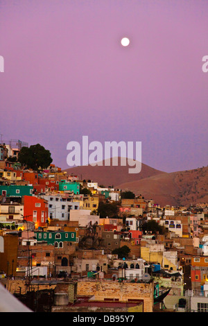 La luna piena sorge sopra le case colorate sul pendio della città culturale di Guanajuato in Messico centrale Foto Stock