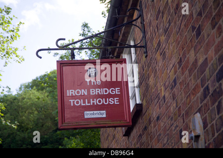 Segno posto per Casa del pedaggio del ponte in ferro attraversa il fiume Severn nello Shropshire, Inghilterra. sul casello muro di mattoni Foto Stock