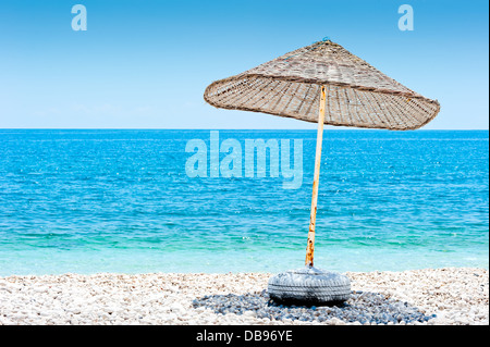 Lone vimini ombrellone in spiaggia Foto Stock