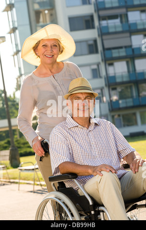 Ricco uomo senior in carrozzella con la moglie per il pensionamento Foto Stock