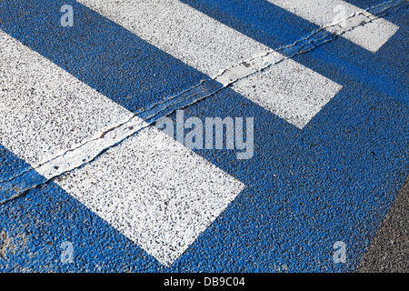 Attraversamento pedonale la segnaletica stradale con linee bianche su asfalto scuro Foto Stock