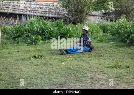 Donna tibetana devotamente gira la sua ruota di preghiera Foto Stock