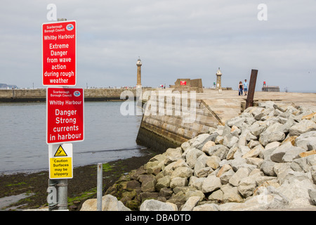 Cartelli di pericolo circa le forti correnti a Whitby Harbour parete, North Yorkshire. Foto Stock