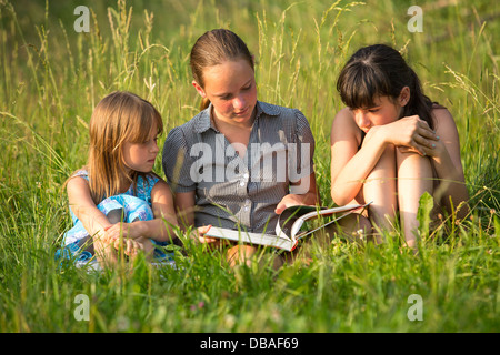 Bambini libro lettura in ambiente naturale insieme. Foto Stock