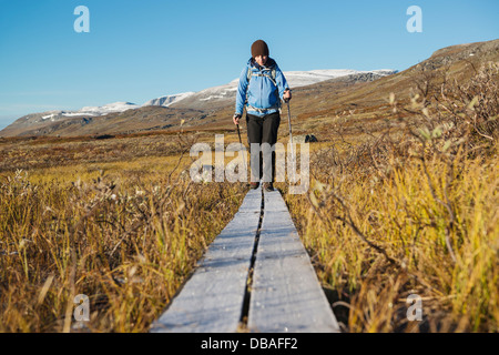 Escursionista femmina passeggiate lungo coperto di brina passerella in legno su Kungsleden trail, Lappland, Svezia Foto Stock